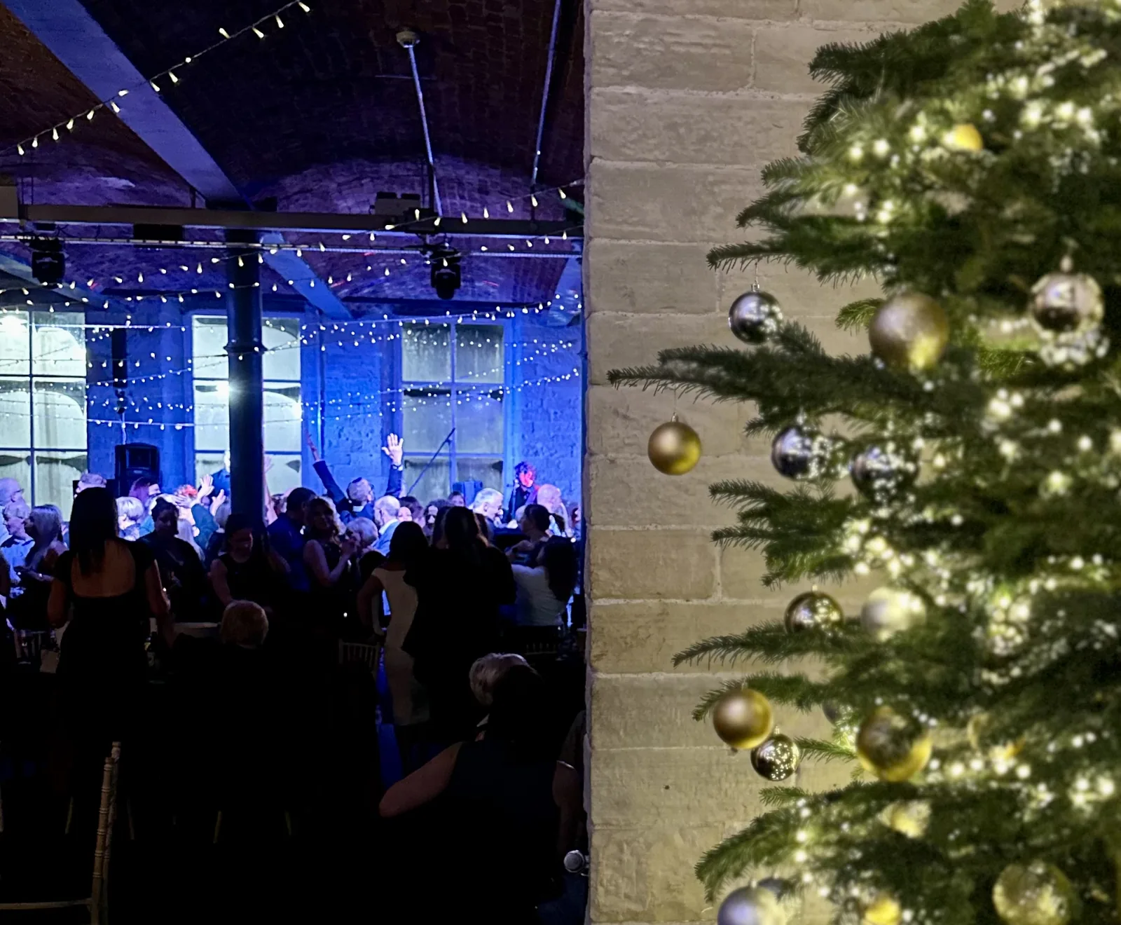 A Christmas party in full swing at The Arches beside a lit Christmas tree