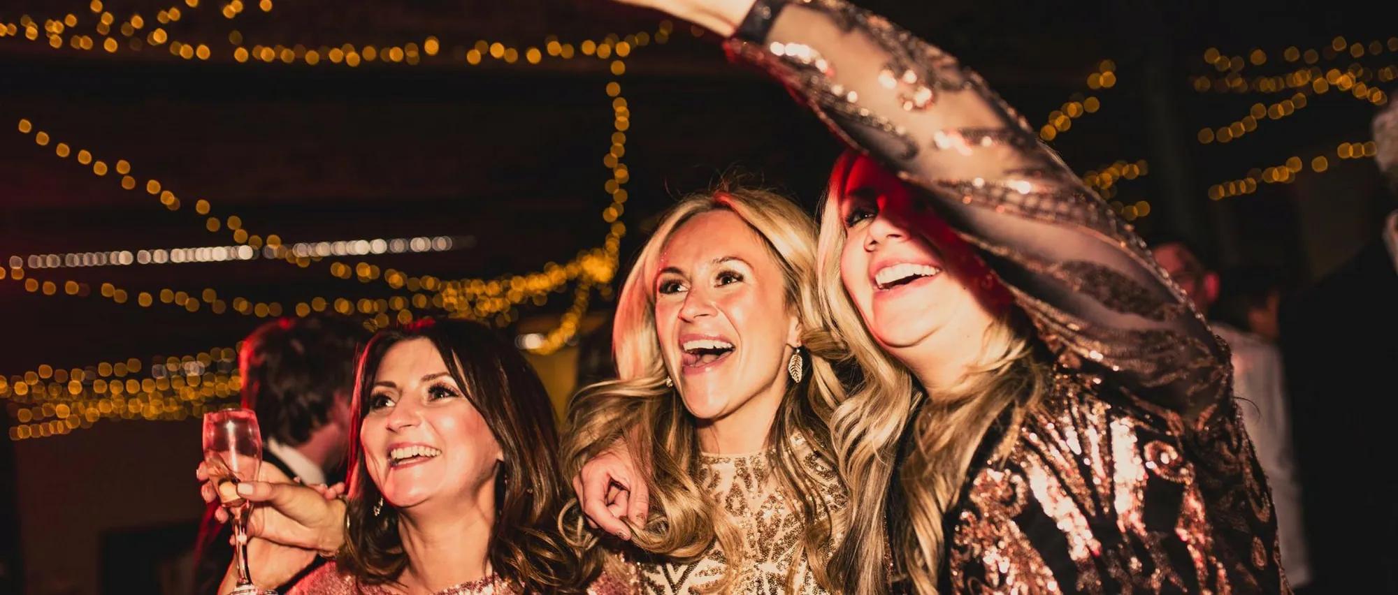 Friends in sequins laughing together at a Christmas party at The Arches